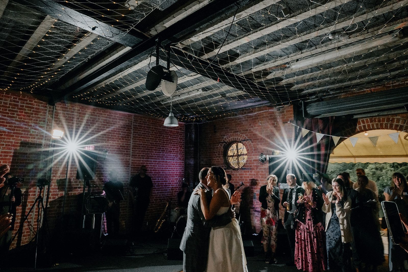 Adrianna and her Dad dancing on the dancefloor in the lower boathouse. Guests are watching on and flashes are in the background. Photo by Matt Fox Photography. 