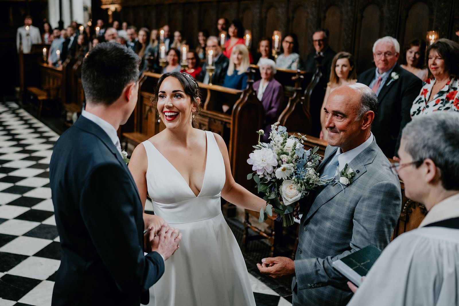 Adrianna greets James at the top of the aisle holding her flower bouquet as her Dad watches smiling. Photo thanks to Matt Fox Photography.