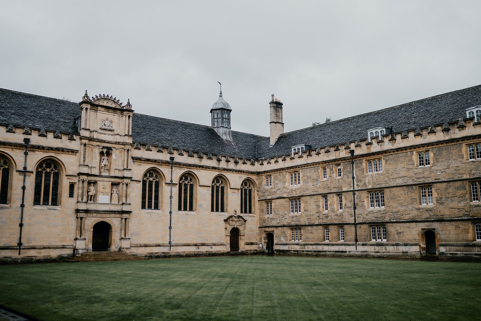 A wide angle photo of the courtyard of Wadham College. There is a large grass square in front of the buildings. Photo thanks to Matt Fox Photography.