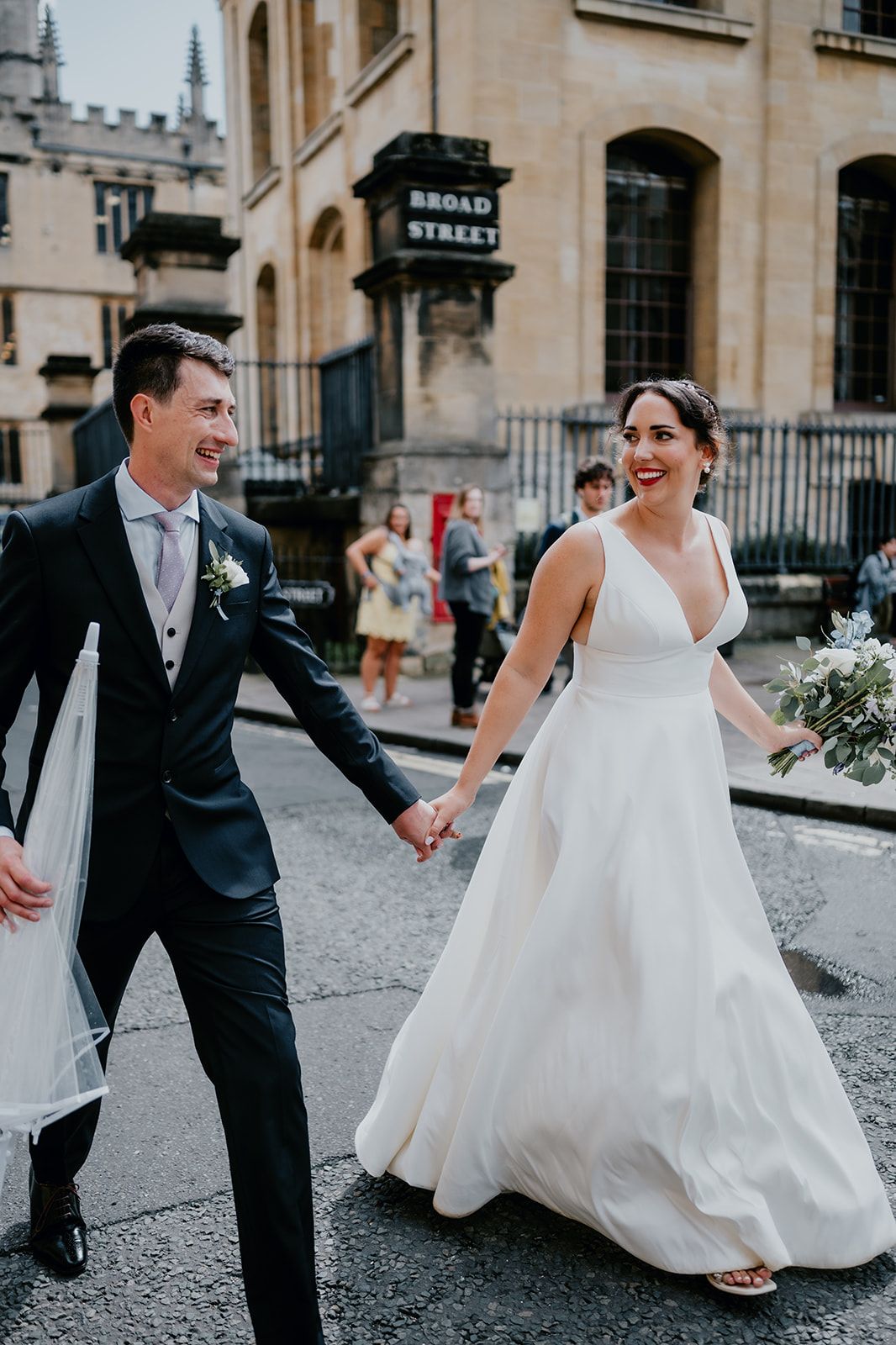 Adrianna and James walking hand in hand along Broad Street in Oxford. Members of the public look on in the background. Photo courtesy of Matt Fox Photography.