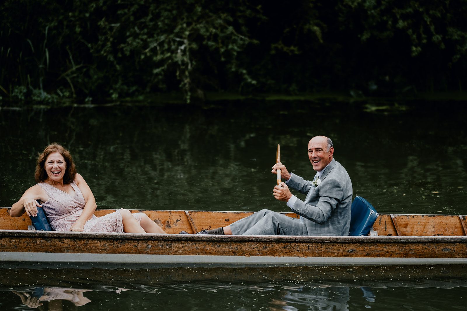 Adrianna's family sitting on a punt boat with a gentleman holding an oar. Both are looking at the camera laughing. Photo courtesy of Matt Fox Photography.