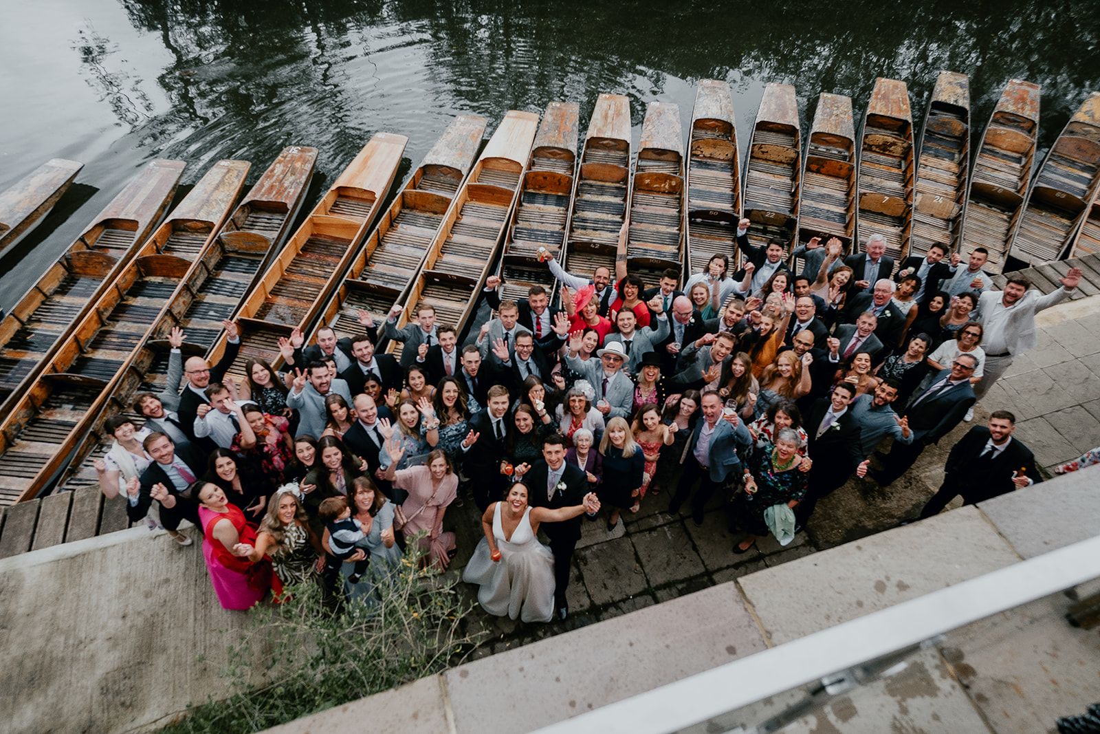 Group photo of all of James and Adrianna's guests stood in front of the parked punting boats on the River Cherwell. Photo courtesy of Matt Fox Photography.